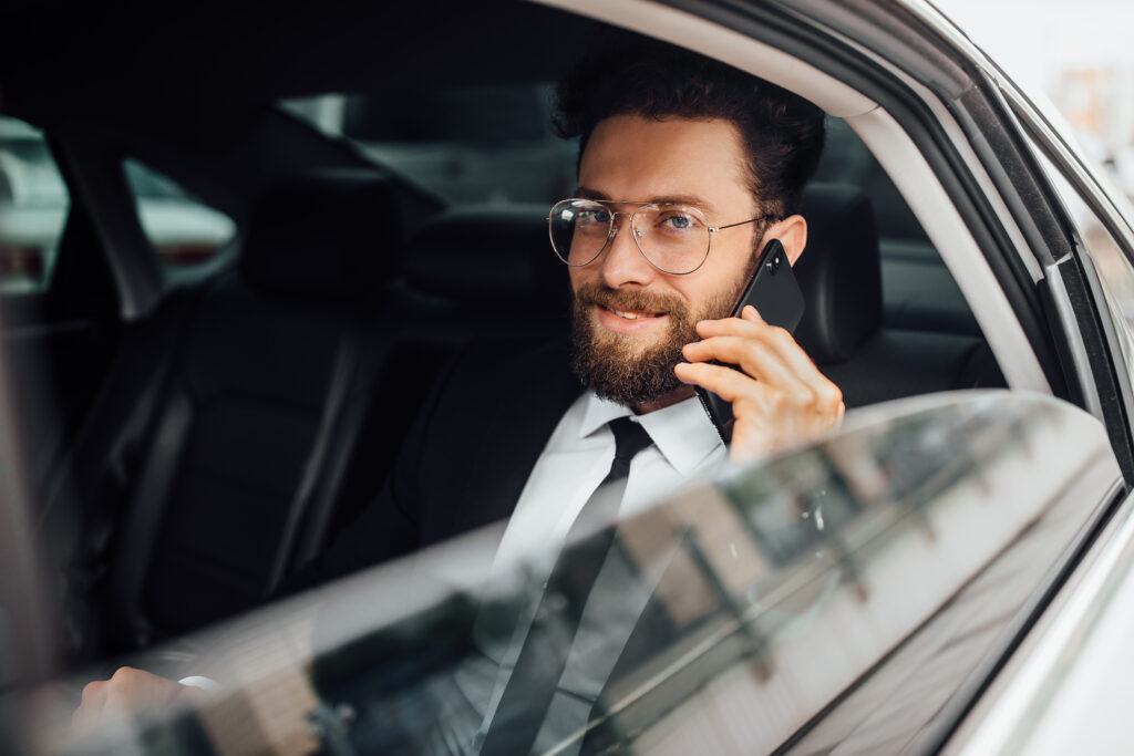 handsome-bearded-smiling-businessman-black-suit-calling-phone-backseat-car
